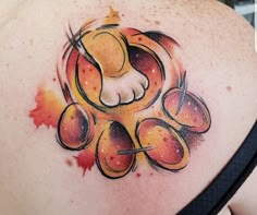 the back of a woman's shoulder with an orange and yellow tattoo design