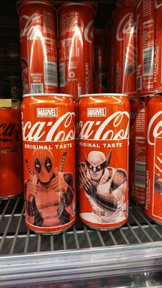 several cans of coca - cola are on display in a grocery store shelf, with deadpool characters painted on them