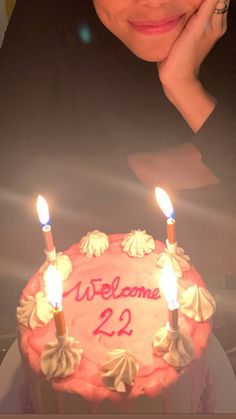 a woman sitting in front of a cake with candles on it and the words welcome 22 written on it