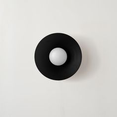 a black object with a white ball in it's center on a white wall