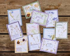 many different cards are arranged on a wooden surface, with flowers in the middle and below them