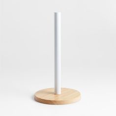 a white candle is on a wooden stand with a round base for the candle holder