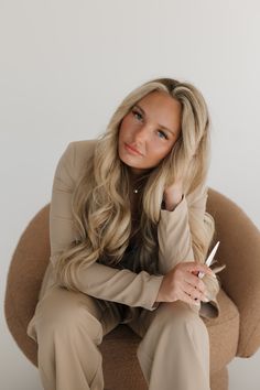 a woman sitting on top of a chair holding a pen