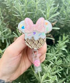 someone holding up a keychain shaped like an ice cream cone with pink sprinkles