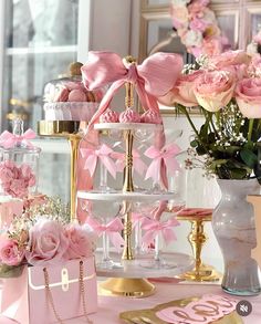 a table topped with lots of pink flowers and glass vases filled with candy bars