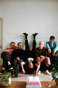 a group of people sitting on top of a couch in front of a white wall