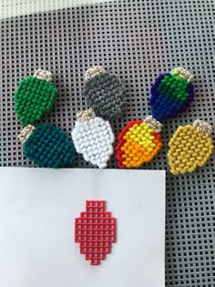 several pieces of bead art are laying on a table next to a piece of paper