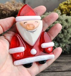 a hand holding a glass santa clause ornament