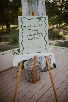 a sign that is sitting on top of a wooden easel in front of a tree