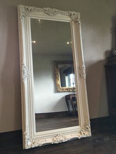 a large white mirror sitting on top of a wooden floor