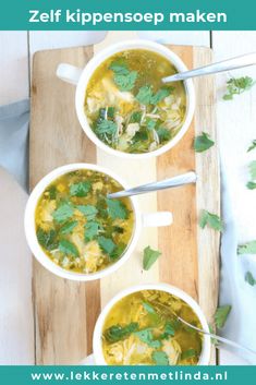 three white bowls filled with soup on top of a wooden cutting board next to green leaves