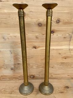 two brass candlesticks sitting on top of a wooden table