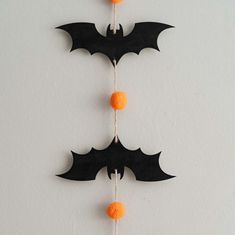 three bats are hanging on a string with orange balls attached to the strings in front of them