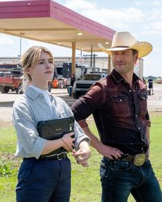 a man and woman standing in front of a gas station