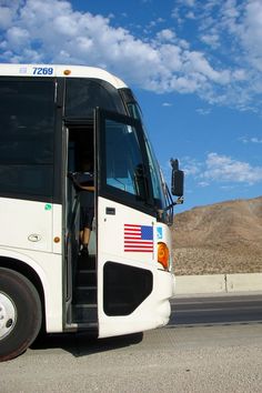 a bus with its door open on the side of the road in front of mountains