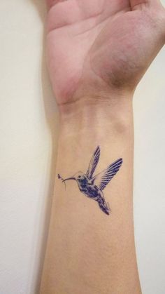 a small tattoo on the wrist of a woman's hand with a hummingbird