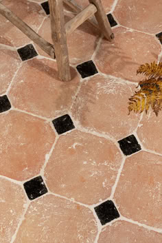 a wooden bench sitting on top of a tiled floor next to a vase filled with flowers