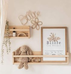 a teddy bear is sitting on a shelf in front of a framed print and some shelves