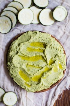 cucumber and avocado dip in a wooden bowl surrounded by sliced cucumbers