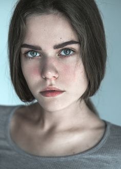 a woman with blue eyes is posing for a photo in front of a white background