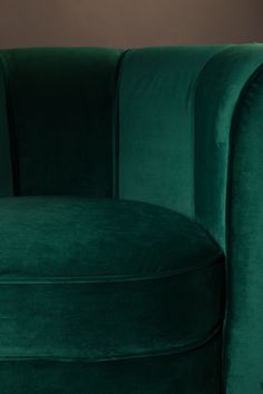 a green velvet chair sitting on top of a wooden floor