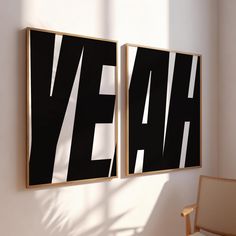 two black and white posters hanging on the wall next to a chair in a room