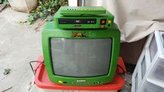 an old green tv sitting on top of a red table