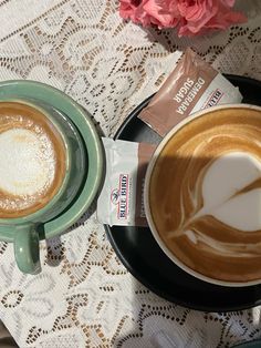 two cups of cappuccino on a saucer with a flower in the background