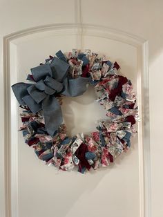 a wreath is hanging on the door with blue and red fabric around it, which has been made out of newspaper strips