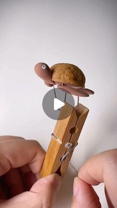 a person is holding a tiny toy snail on top of a piece of wood and string