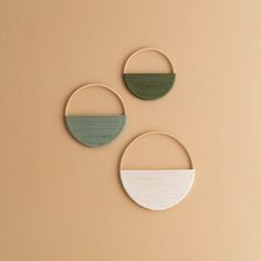 three circular wooden wall hangings with two different colors and shapes on each one side