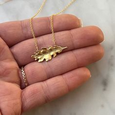 This necklace features a solid brass oak leaf pendant gracefully suspended on a 14k gold fill chain. The oak leaf's timeless design and warm brass hue offer a touch of natural charm. With a clean and minimalist aesthetic, the necklace embraces simplicity, allowing the intricate details of the oak leaf to shine. The 14k gold fill chain adds a hint of elegance, creating a seamless fusion of classic and contemporary style. Durable and versatile, this necklace is a celebration of the enduring beauty found in the simplicity of nature. ● 16" Chain ● 14k Gold fill chain ● Solid Brass Oak Leaf Oak Leaf Necklace, Oak Leaf, Women's Jewelry And Accessories, Leaf Necklace, Leaf Pendant, Minimalist Aesthetic, Gold Filled Chain, Intricate Details, Language English