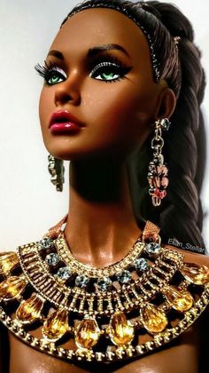 a barbie doll wearing a gold necklace and matching earring set with earrings on her head