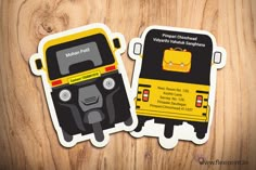 two yellow and black bus stickers sitting on top of a wooden table