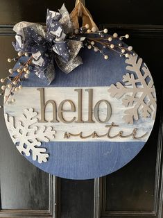 a wooden sign that says hello winter hanging on a door with snowflakes around it