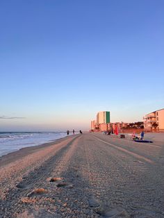 A tranquil sunrise view of Myrtle Beach with footprints in the sand, beach chairs set up, and buildings lining the shore, taken from Garden City Beach. Coastal Living, The Ocean, Things To Do, Beauty