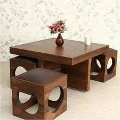 a wooden table with two stools and a vase on top