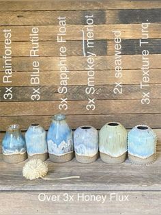 seven vases sitting on top of a wooden table next to a sign that says over 3x honey flux