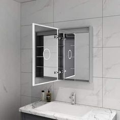 a bathroom with a sink and mirror on the wall above it is white marble tiles