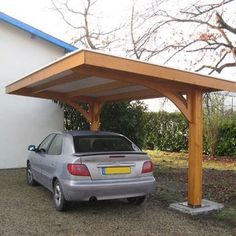 a car is parked under a wooden carport