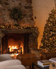 a living room filled with furniture and a fire place next to a christmas tree in front of a stone fireplace