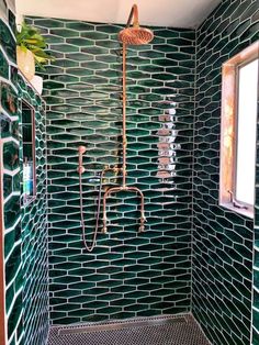 a bathroom with green tiles on the wall and shower head in the corner, next to a window