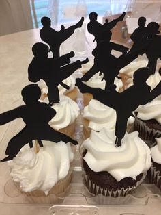 cupcakes with white frosting and black silhouettes are on a clear tray