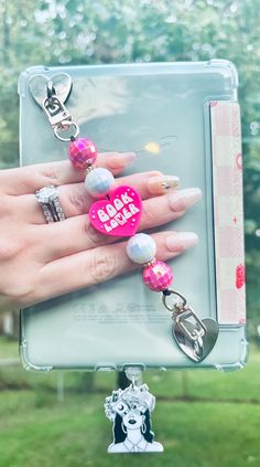 a woman's hand holding a pink and white keychain