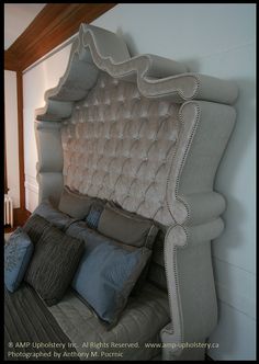 an upholstered bed with blue and gray pillows