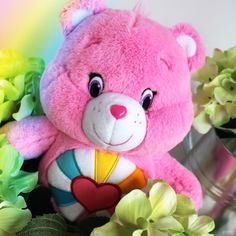 a pink teddy bear sitting next to flowers