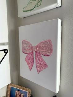 two pictures are hanging on the wall next to each other, one with a pink bow