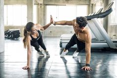 a man and woman doing push ups in a gym