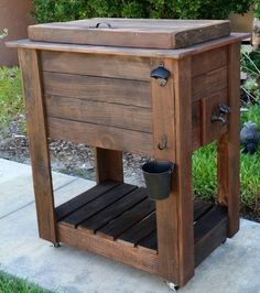 a wooden stand with a potted plant in it on the sidewalk next to some grass