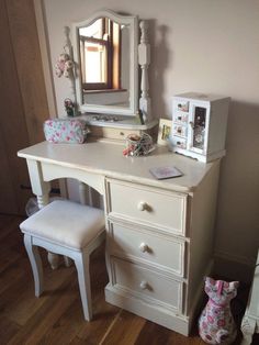 a white dresser with a mirror and stool